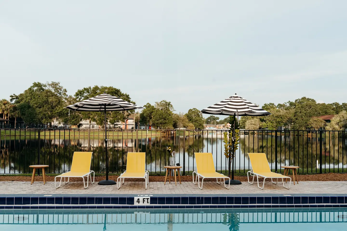 Pool with bright yellow pool chairs and umbrella shading .